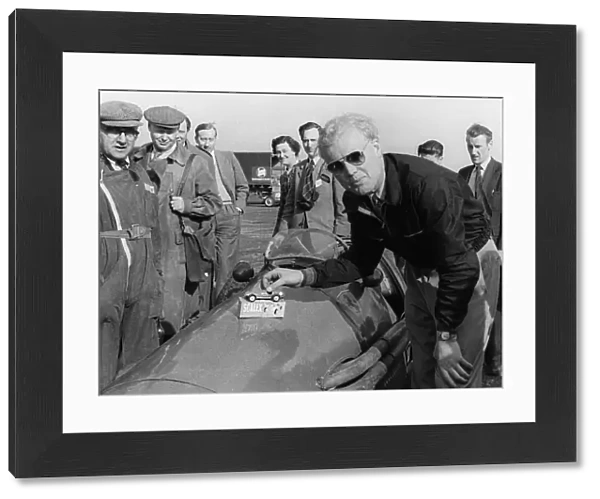 Mike Hawthorn admiring a toy model Ferrari on his racing Ferrari. Creator: Unknown