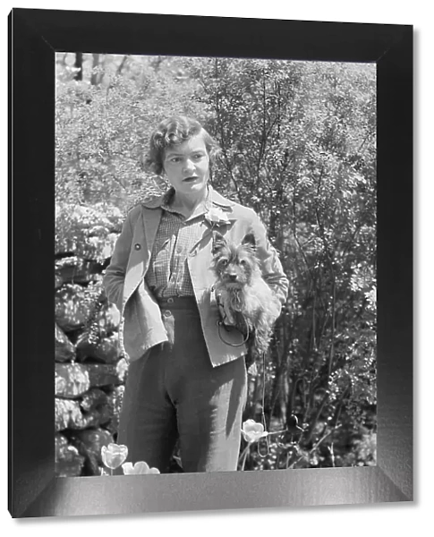 DeLamar, Alice, Miss, with dog, standing outdoors, between 1927 and 1942. Creator: Arnold Genthe