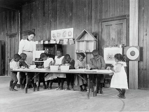 Eight African American children, in kindergarten, learning washing and ironing... 1899 or 1900. Creator: Frances Benjamin Johnston