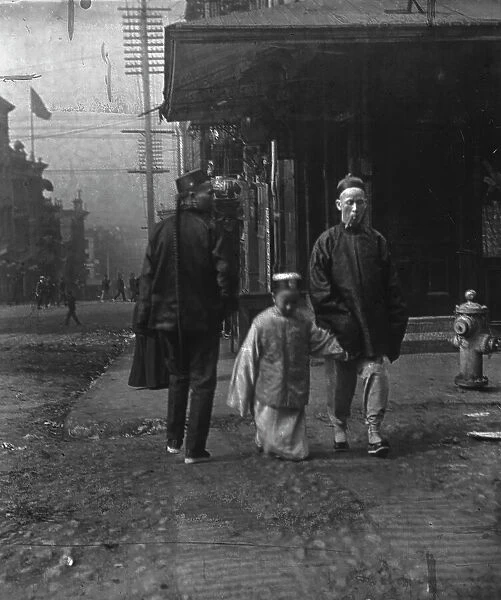 Boy and a man smoking a cigar crossing the street, San Francisco, between 1896 and 1906. Creator: Arnold Genthe