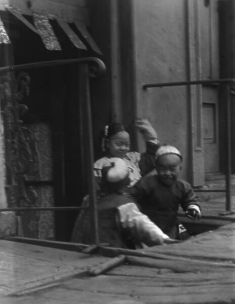 Three children in front of a cellar door, Chinatown, San Francisco, between 1896 and 1906. Creator: Arnold Genthe