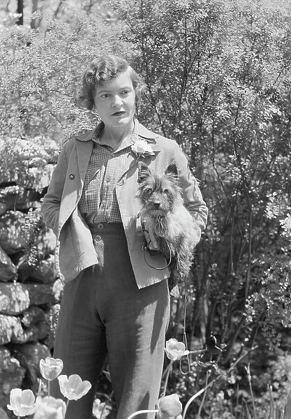 DeLamar, Alice, Miss, with dog, standing outdoors, between 1927 and 1942. Creator: Arnold Genthe