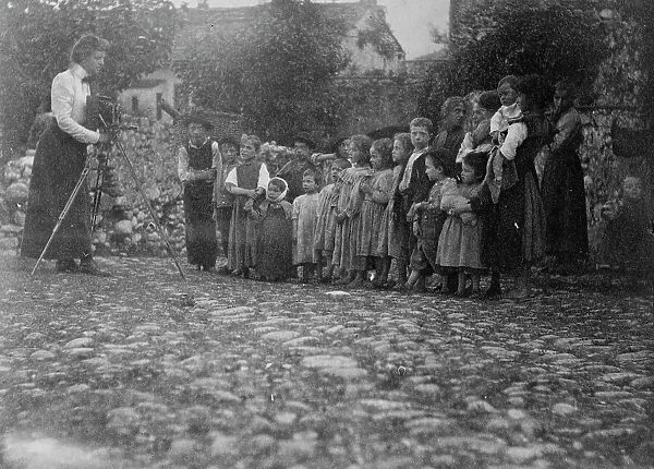 Frances Benjamin Johnston photographing a group of people, mostly children, in Europe, 1900. Creator: Unknown