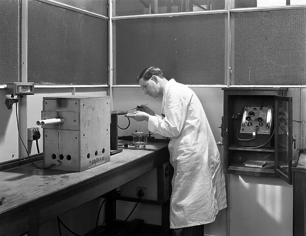 Lab tachnician using a table top test furnace, Sheffield, South Yorkshire, 1962. Artist