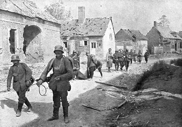 A travers le champ de bataille; prisonniers allemands traversant un village reconquis... 1918. Creator: Unknown