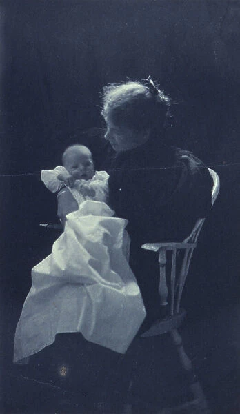 Woman, sitting in chair, holding an infant, full-length portrait, c1900. Creator: Sarah J. Eddy