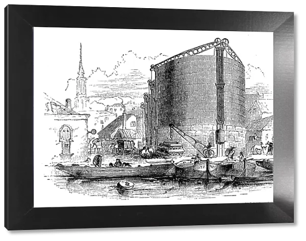 Exterior view of City of London Gasworks, showing gasometers and coal barges at the quay, 1876