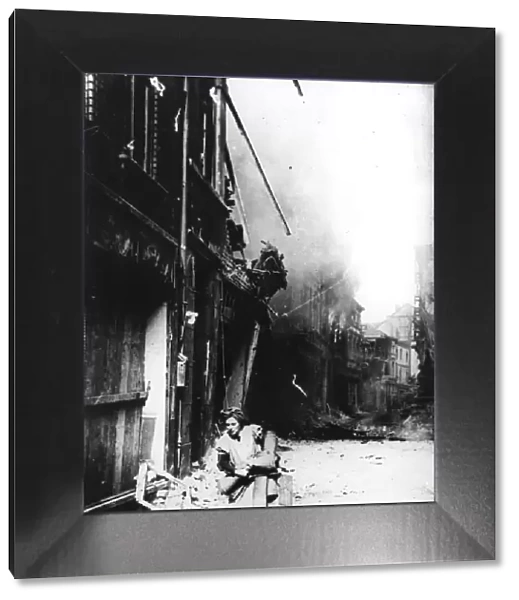 A woman leaving her burning house in a bombed street, Germany, 1945