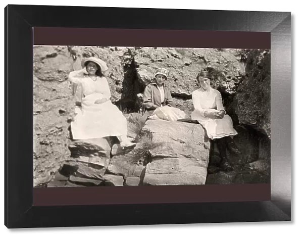 Three women relaxing on rocks, early 20th century