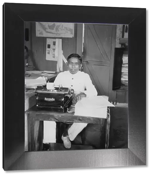A young man sitting at a typewriter, Indonesia, 20th century