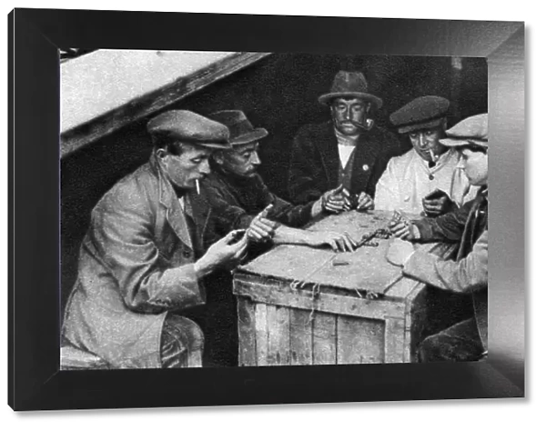 A bargee and his mates play dominoes in the hold of a canal boat, 1926-1927