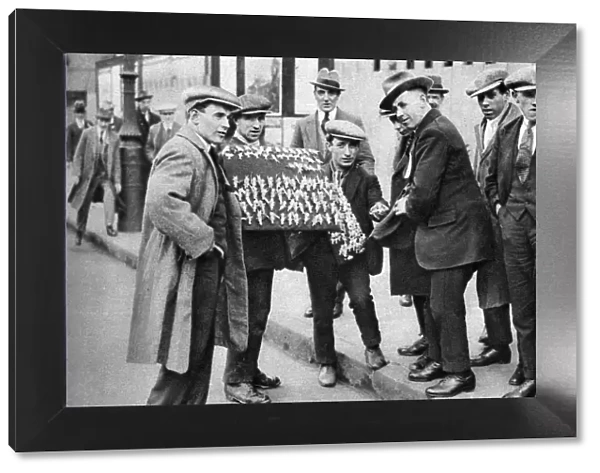 Street hawker selling football favours in Kings Cross, London, 1911 (1926-1927)