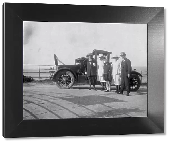 A group of people in front of their car at the seaside, c1920s(?)