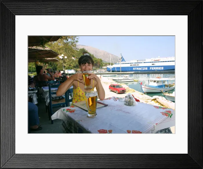 Framed Print : Woman enjoying a drink in a harbourside taverna, Poros, Kefalonia, Greece Framed Print : Woman enjoying a drink in a harbourside taverna, Poros, Kefalonia, Greece