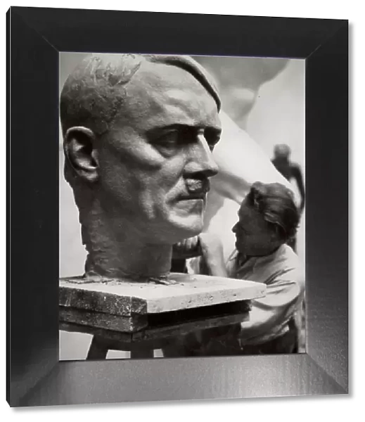 A sculptor working on a large portrait bust of Adolf Hitler, Germany, 1936. Artist
