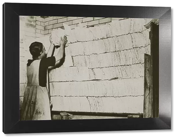 Stacking unleavened bread for the Passover in a Jewish bakery, 20th century. Artist