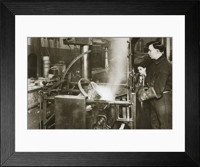 Framed Print : Making money; lowering a pot of liquid metal into a machine, 20th century. Artist Framed Print : Making money; lowering a pot of liquid metal into a machine, 20th century. Artist