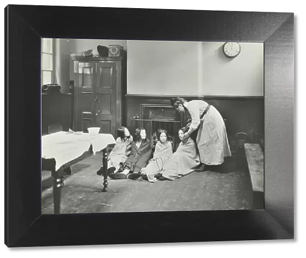 Girls drying their hair by the fire after a bath, Chaucer Cleansing Station, London, 1911