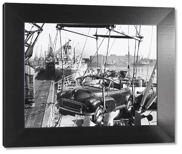Morris Minor convertible craned onto ship for export at Cardiff docks. Creator: Unknown