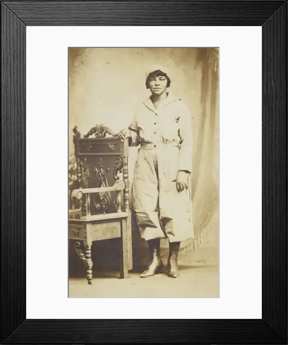 Framed Print : Photographic postcard of a woman standing next to a wooden chair, 1918-1930 Framed Print : Photographic postcard of a woman standing next to a wooden chair, 1918-1930