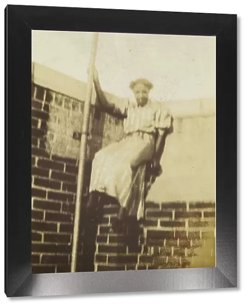 Photographic print of a woman on a brick wall, early 20th century. Creator: Unknown