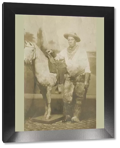 Postcard of a man posing in a Western scene in a photography studio, early 20th century
