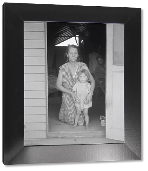 Migrant mother and child at doorway of steel shelter, FSA camp, Tulare County, 1939. Creator: Dorothea Lange
