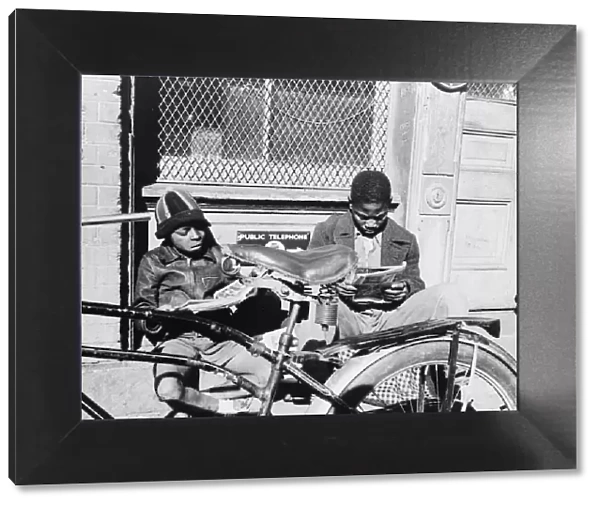 Two Negro boys reading the funnies on a doorstep, Washington, D. C. 1942. Creator: Gordon Parks