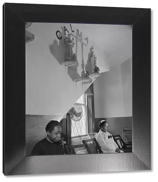 Sitting beneath the emblem of the crucifixion of Jesus on Calvary, Washington, D. C. 1942. Creator: Gordon Parks