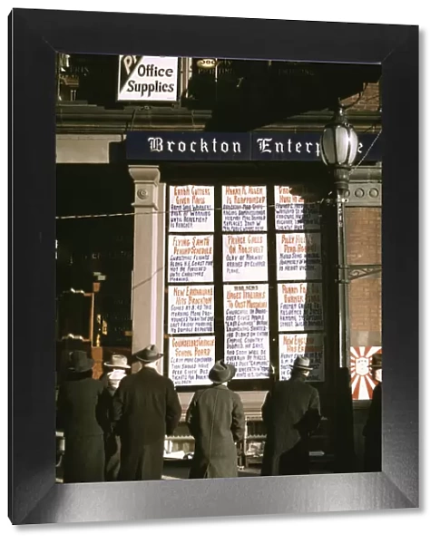 Men and a woman reading headlines posted in street-corner window of Brockton... Mass. 1940. Creator: Jack Delano