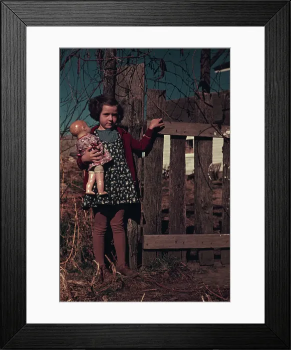 Framed Print : Girl with doll standing by fence, between 1941 and 1942. Creator: Unknown Framed Print : Girl with doll standing by fence, between 1941 and 1942. Creator: Unknown
