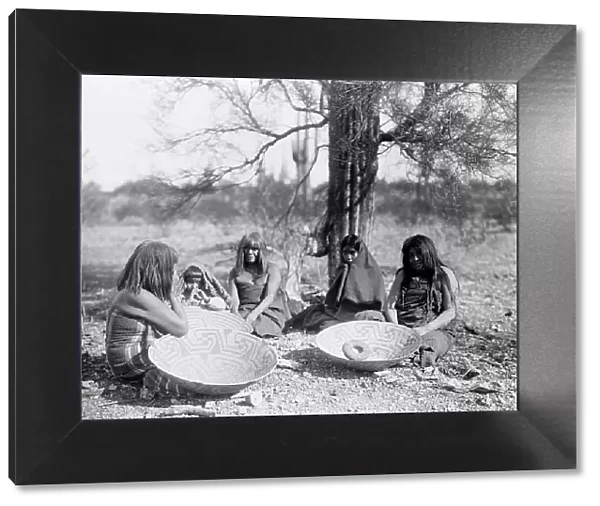 Maricopa group, Arizona. Four women and a child seated on ground with three large basket trays, c1907 Creator: Edward Sheriff Curtis