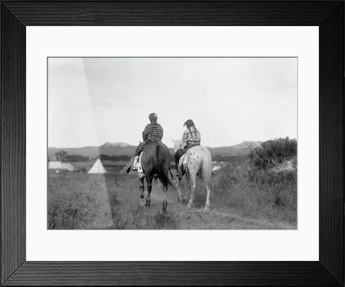 Framed Print : Two daughters of a chief on horseback, riding away from camera toward tents in background, c1907. Creator: Edward Sheriff Curtis Framed Print : Two daughters of a chief on horseback, riding away from camera toward tents in background, c1907. Creator: Edward Sheriff Curtis