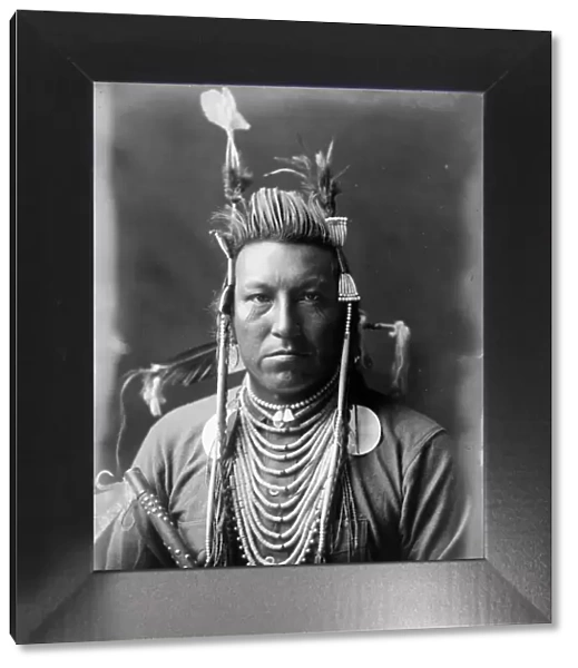 Swallow Bird, Crow Indian, Montana, head-and-shoulders portrait, facing front, painted... c1908. Creator: Edward Sheriff Curtis