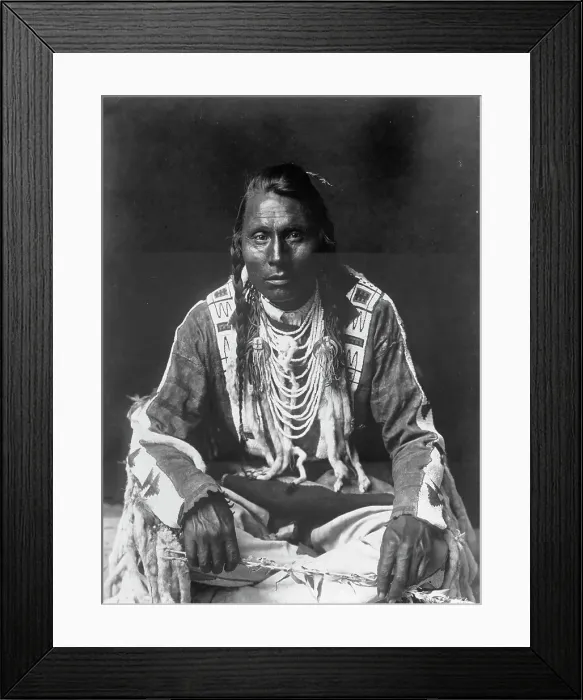 Framed Print : Wades in Water, Piegan Indian, full-length portrait, seated on floor, facing front... c1910. Creator: Edward Sheriff Curtis Framed Print : Wades in Water, Piegan Indian, full-length portrait, seated on floor, facing front... c1910. Creator: Edward Sheriff Curtis