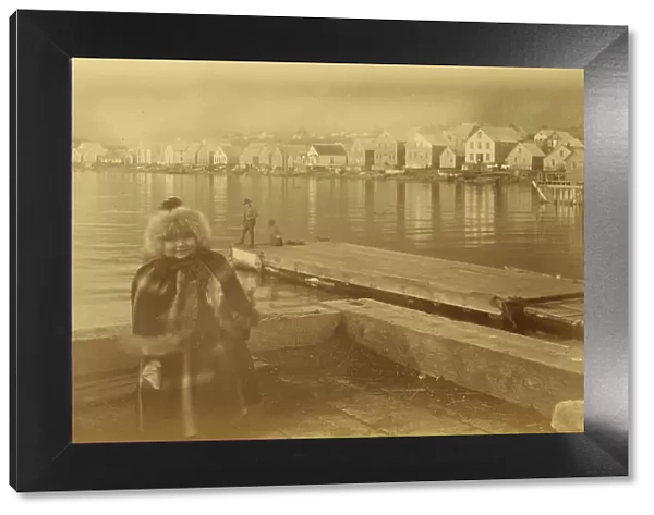 Unidentified young girl standing on wharf, with buildings along waterfront...1894 or 1895. Creator: Alfred Lee Broadbent