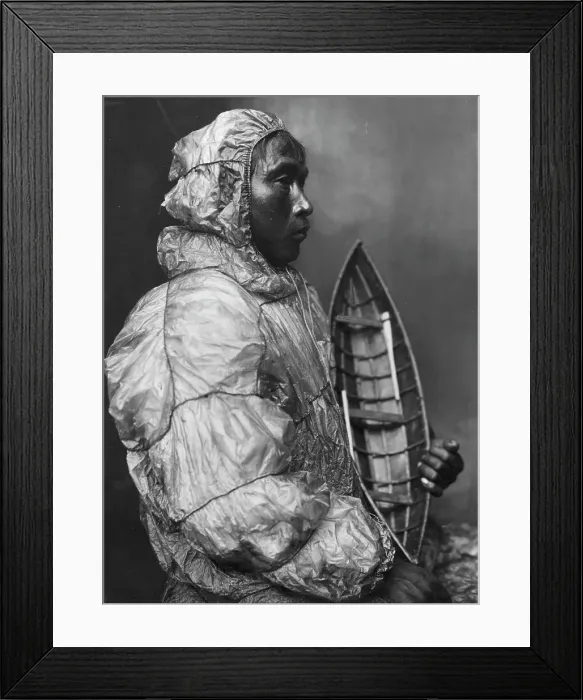 Framed Print : Kayaker wearing water-proof jacket with toy boat he made for his son, between c1900 and c1930. Creator: Lomen Brothers Framed Print : Kayaker wearing water-proof jacket with toy boat he made for his son, between c1900 and c1930. Creator: Lomen Brothers