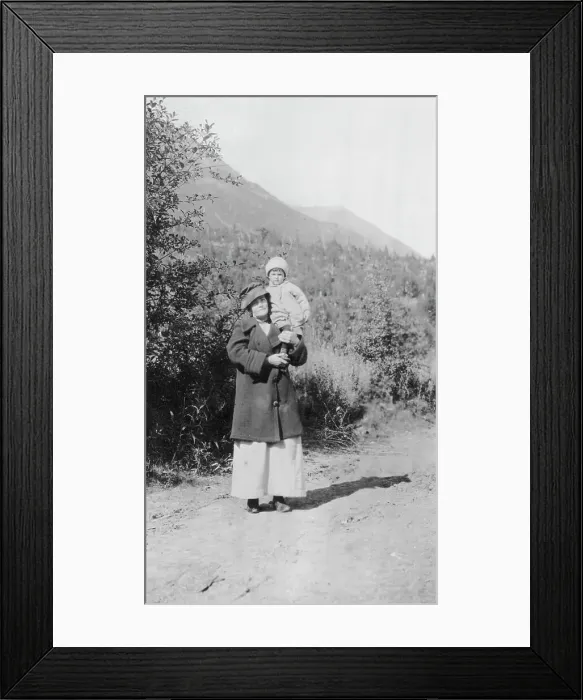 Framed Print : Woman standing on dirt road holding child; mountains in background, between c1900 and 1916. Creator: Unknown Framed Print : Woman standing on dirt road holding child; mountains in background, between c1900 and 1916. Creator: Unknown