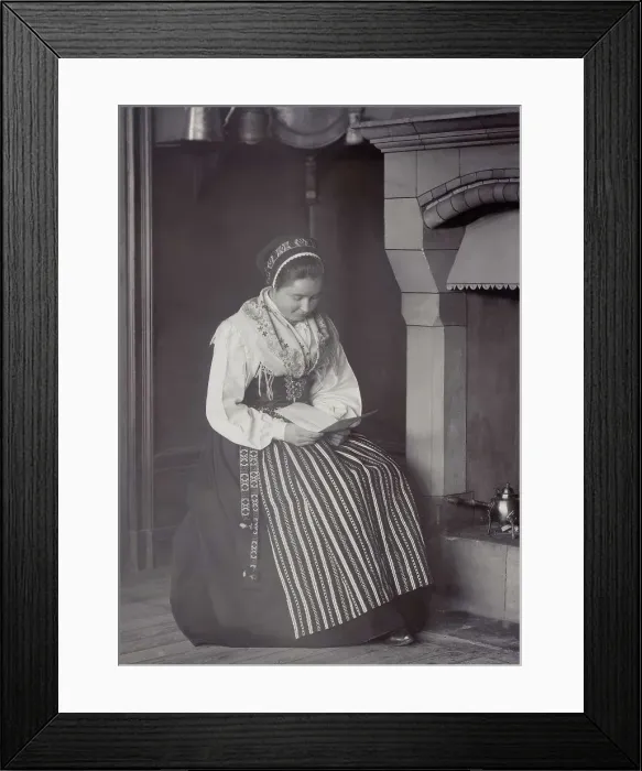 Framed Print : A woman sits in front of a fireplace and reads dressed in a Dalarna costume, 1886-1920. Creator: Helene Edlund Framed Print : A woman sits in front of a fireplace and reads dressed in a Dalarna costume, 1886-1920. Creator: Helene Edlund