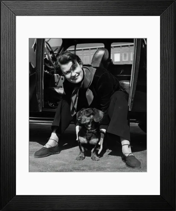 Framed Print : Photographer Kerstin Bernhard sits in the doorway of her car and holds a dachshund, 1955-1960. Creator: Unknown Framed Print : Photographer Kerstin Bernhard sits in the doorway of her car and holds a dachshund, 1955-1960. Creator: Unknown