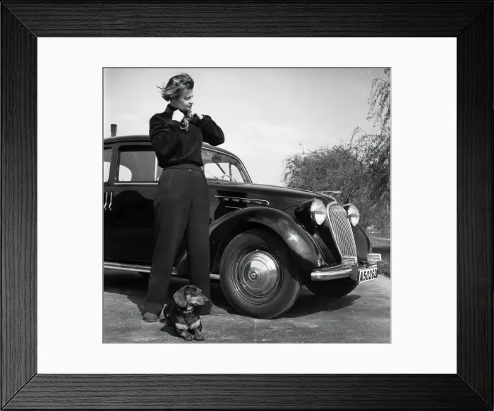 Framed Print : Photographer Kerstin Bernhard stands next to a car with her dachshund, 1955-1960. Creator: Unknown Framed Print : Photographer Kerstin Bernhard stands next to a car with her dachshund, 1955-1960. Creator: Unknown