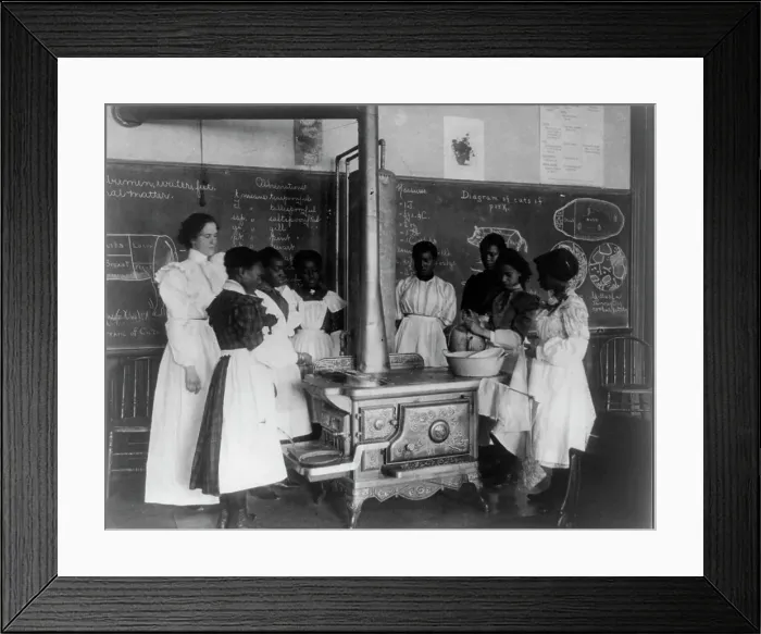 Framed Print : African American schoolgirls with teacher, learning to cook on a wood stove in classroom, (1899?). Creator: Frances Benjamin Johnston Framed Print : African American schoolgirls with teacher, learning to cook on a wood stove in classroom, (1899?). Creator: Frances Benjamin Johnston