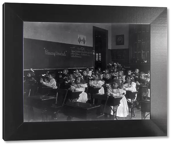Children in a classroom blowing pinwheels in a Washington, D.C. grade school, (1899?). Creator: Frances Benjamin Johnston
