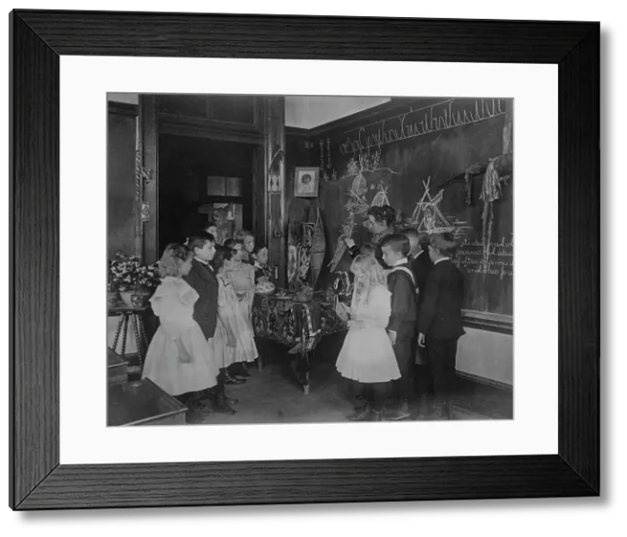 Framed Print : Teacher showing students Native American handicrafts at a school in Washington, D.C. (1899?). Creator: Frances Benjamin Johnston Framed Print : Teacher showing students Native American handicrafts at a school in Washington, D.C. (1899?). Creator: Frances Benjamin Johnston
