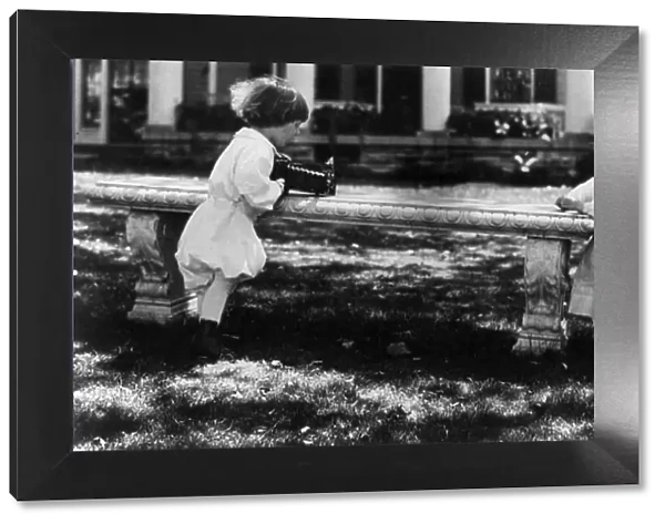 One child aiming camera, on bench, at another child, Washington, D.C. between c1890 and c1910. Creator: Frances Benjamin Johnston
