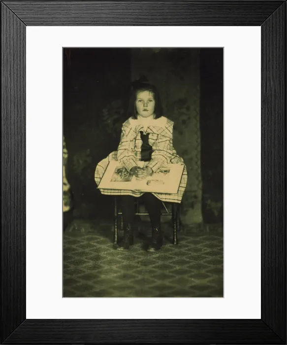Framed Print : Girl in a plaid dress seated with a book in her lap, c1900. Creator: Mathilde Weil Framed Print : Girl in a plaid dress seated with a book in her lap, c1900. Creator: Mathilde Weil