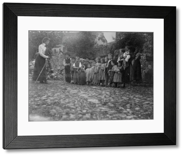 Framed Print : Frances Benjamin Johnston photographing a group of people, mostly children, in Europe, 1900. Creator: Unknown Framed Print : Frances Benjamin Johnston photographing a group of people, mostly children, in Europe, 1900. Creator: Unknown