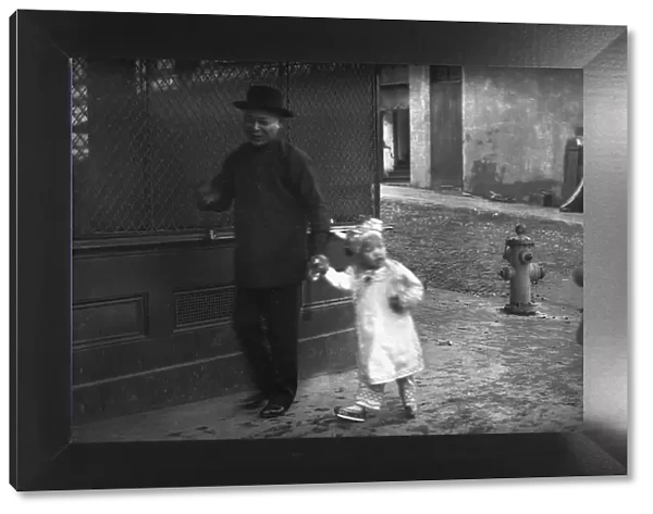 Man and a young child walking down a street, Chinatown, San Francisco, between 1896 and 1906. Creator: Arnold Genthe