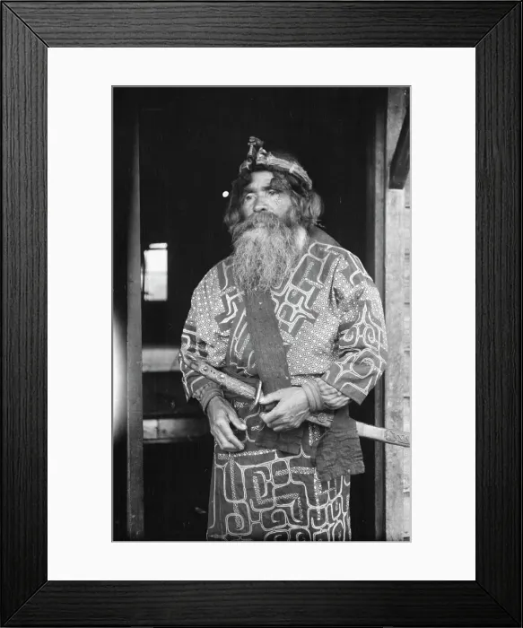 Framed Print : Ainu chief wearing a headdress and holding a sword standing in a doorway, 1908. Creator: Arnold Genthe Framed Print : Ainu chief wearing a headdress and holding a sword standing in a doorway, 1908. Creator: Arnold Genthe