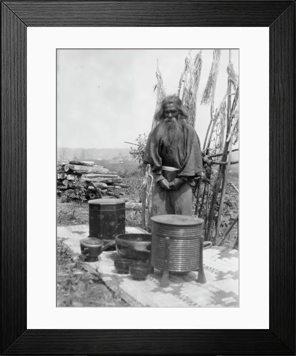 Framed Print : Ainu man standing outdoors on a mat covered with clay containers, 1908. Creator: Arnold Genthe